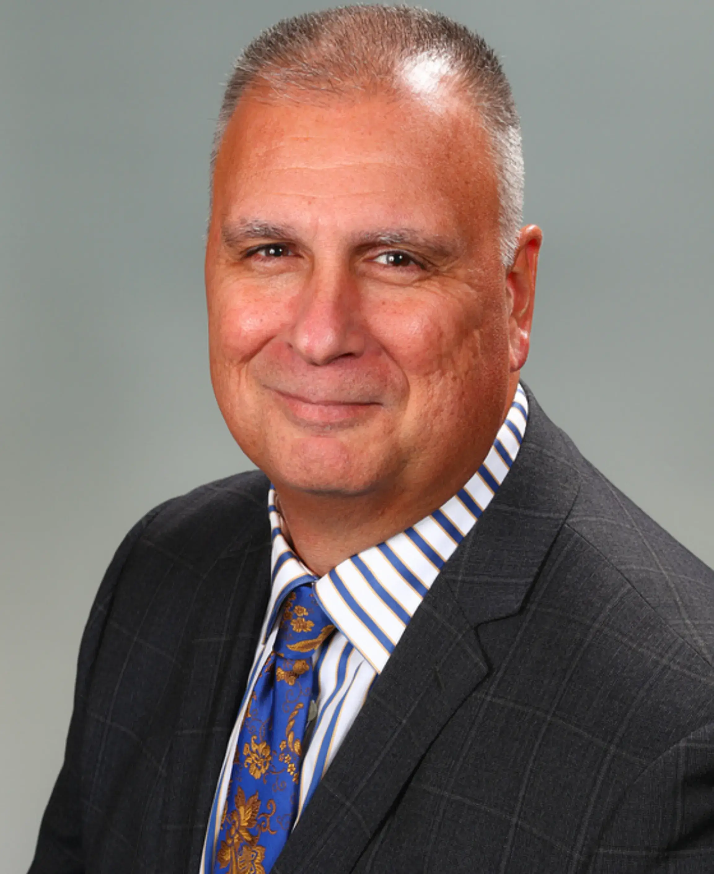 Man in suit with striped shirt smiling.