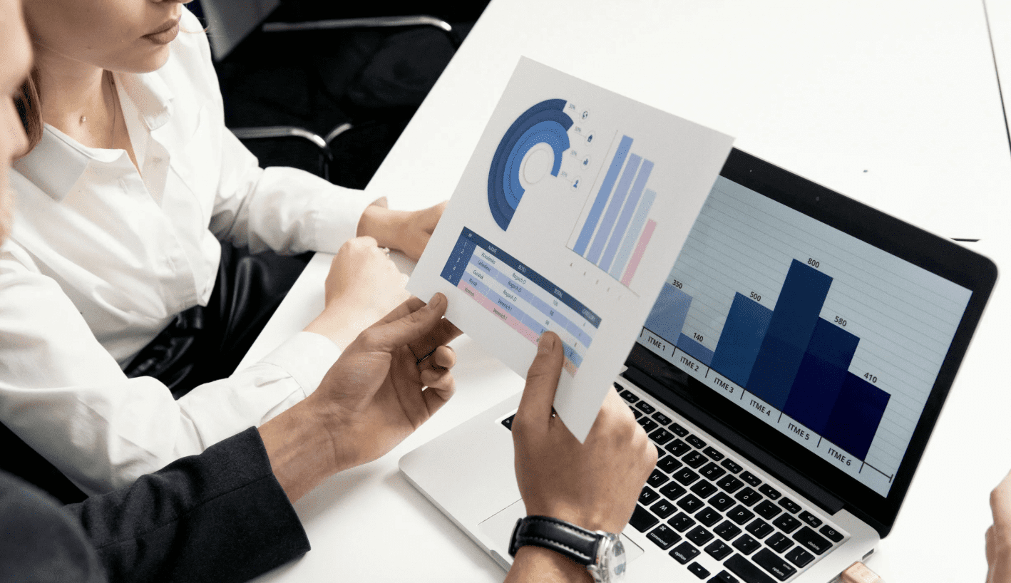 Two people analyzing a printed report with charts.