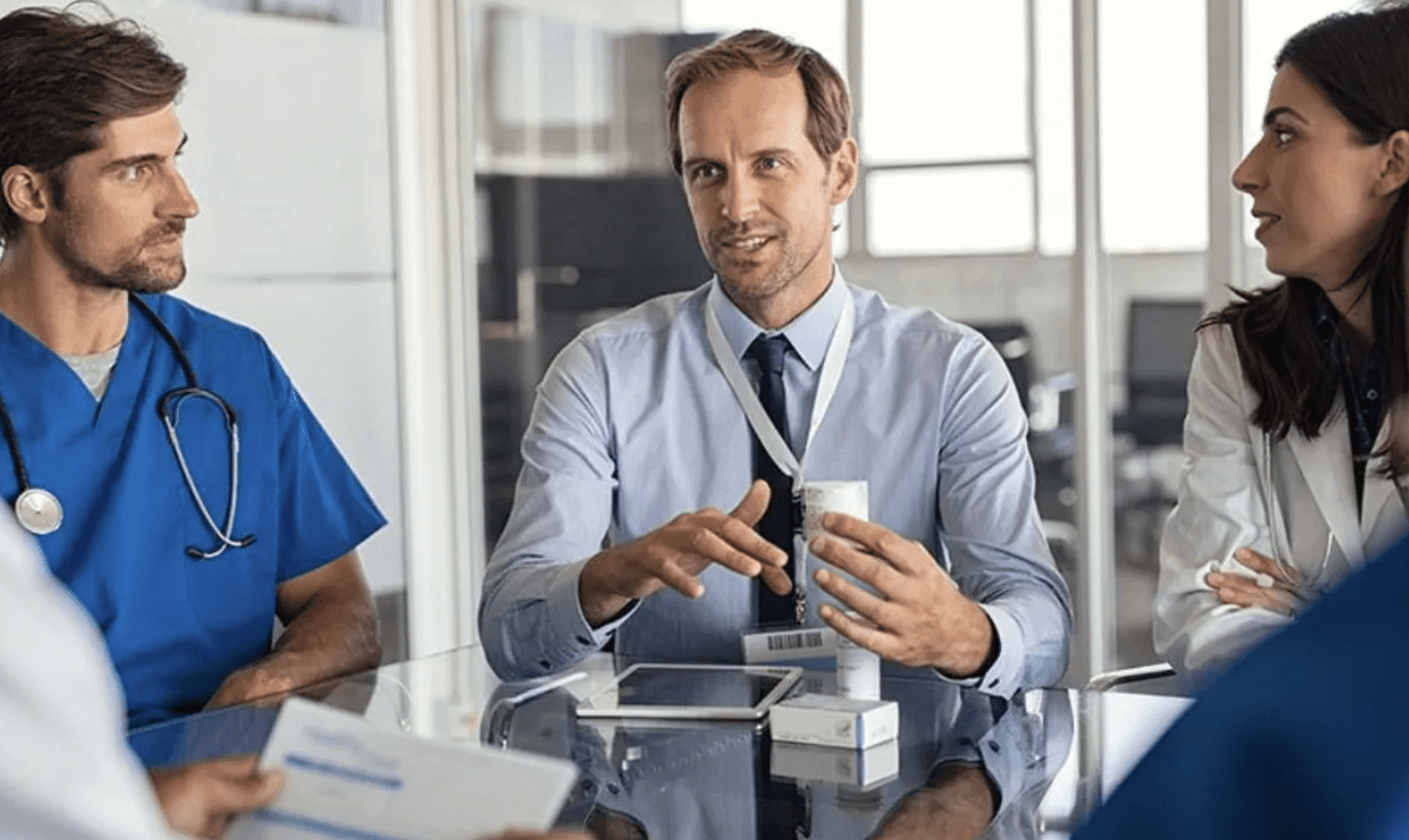 A man in a shirt and tie holding a small medical device.