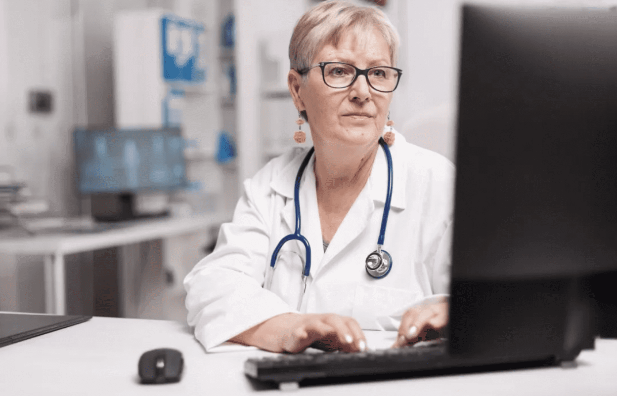 A female doctor working on a laptop in a medical office.